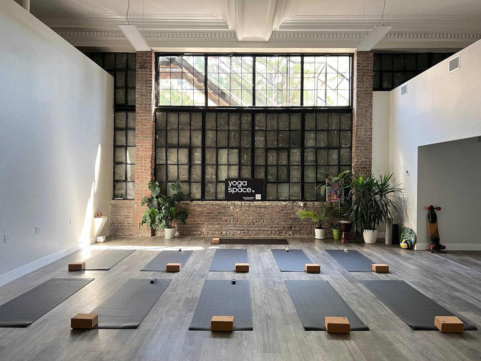Bright yoga studio with brick walls and a large steel window